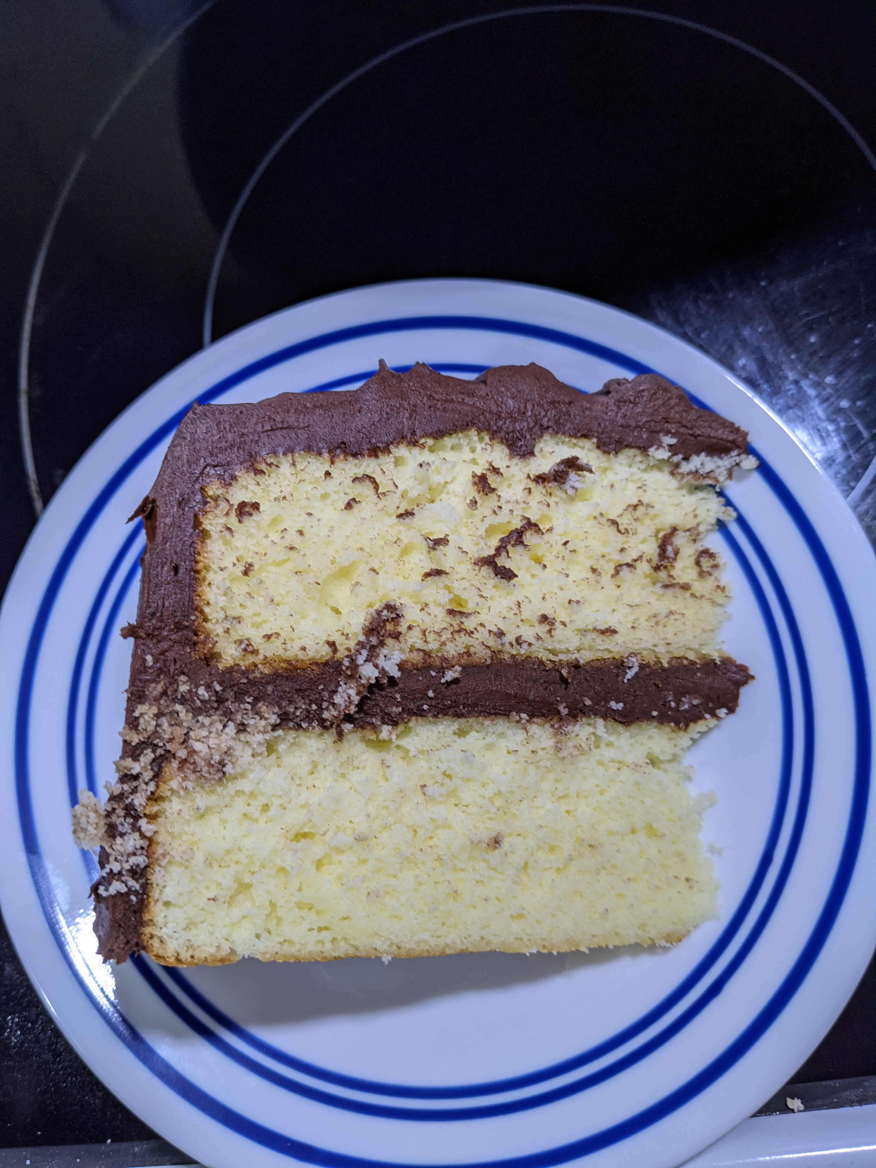 A slice of fluffy yellow cake with chocolate frosting