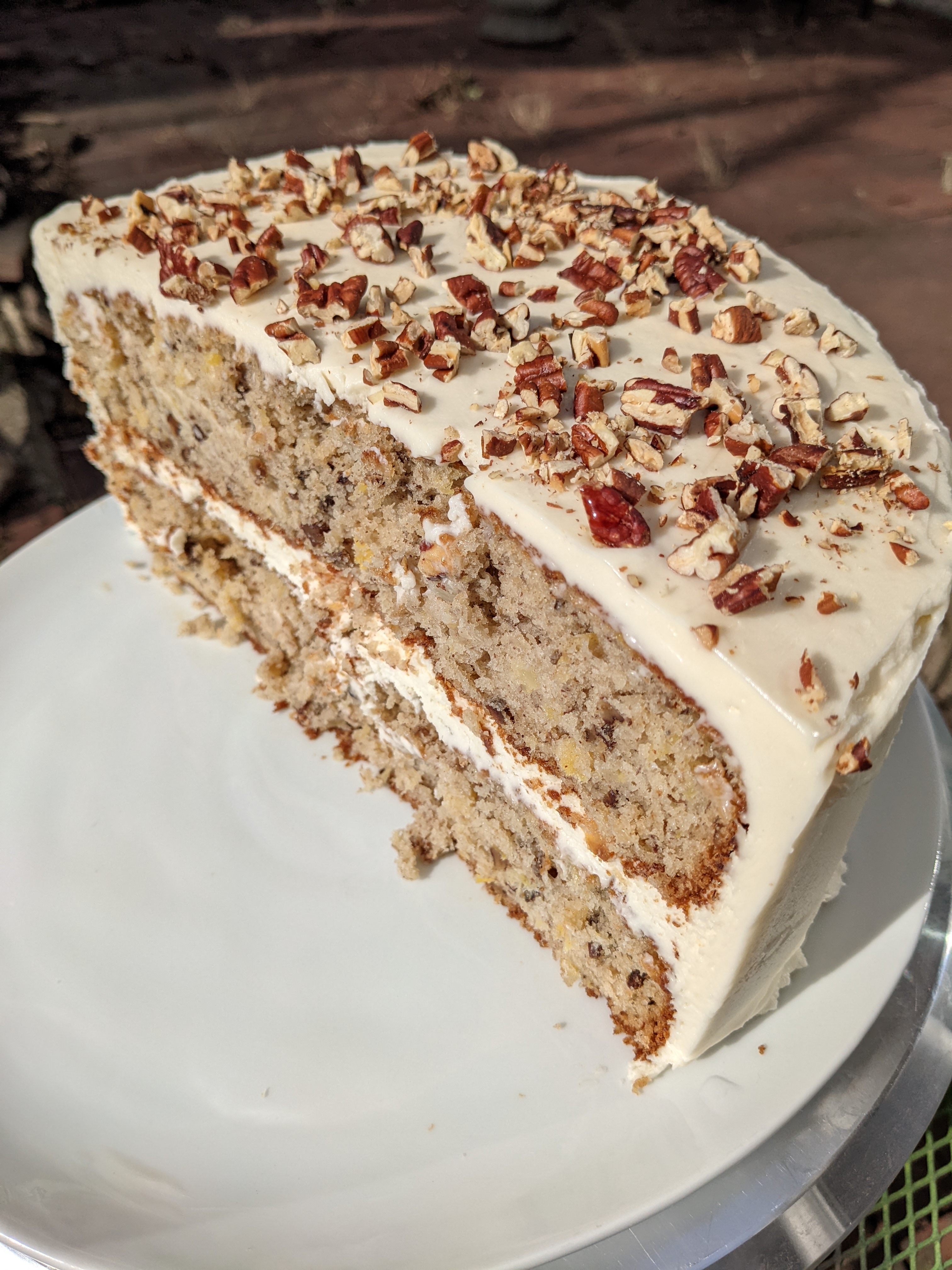 A brown cake with white frosting covered in brown nuts