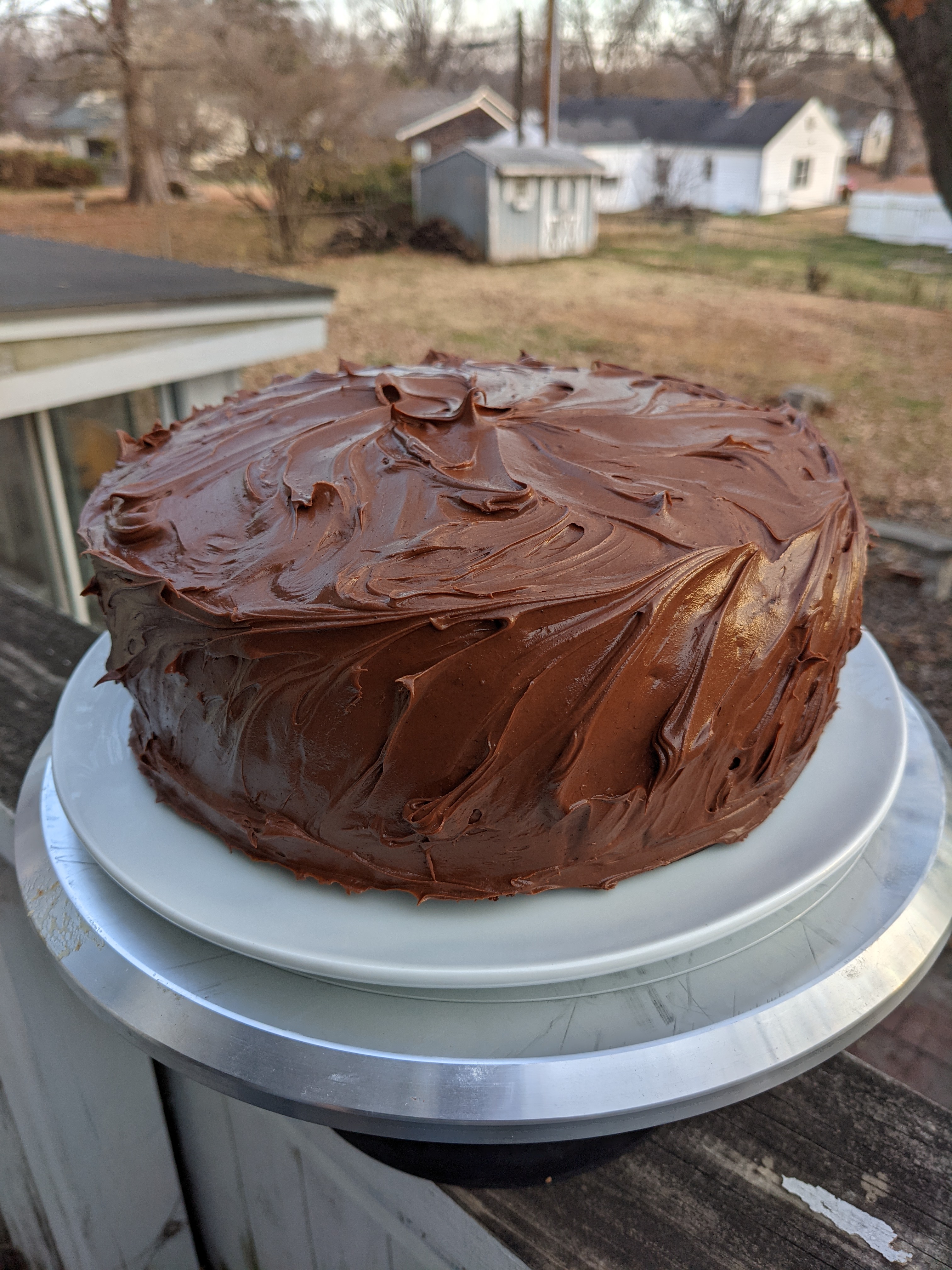A chocolate cake covered with dollops of chocolate frosting
