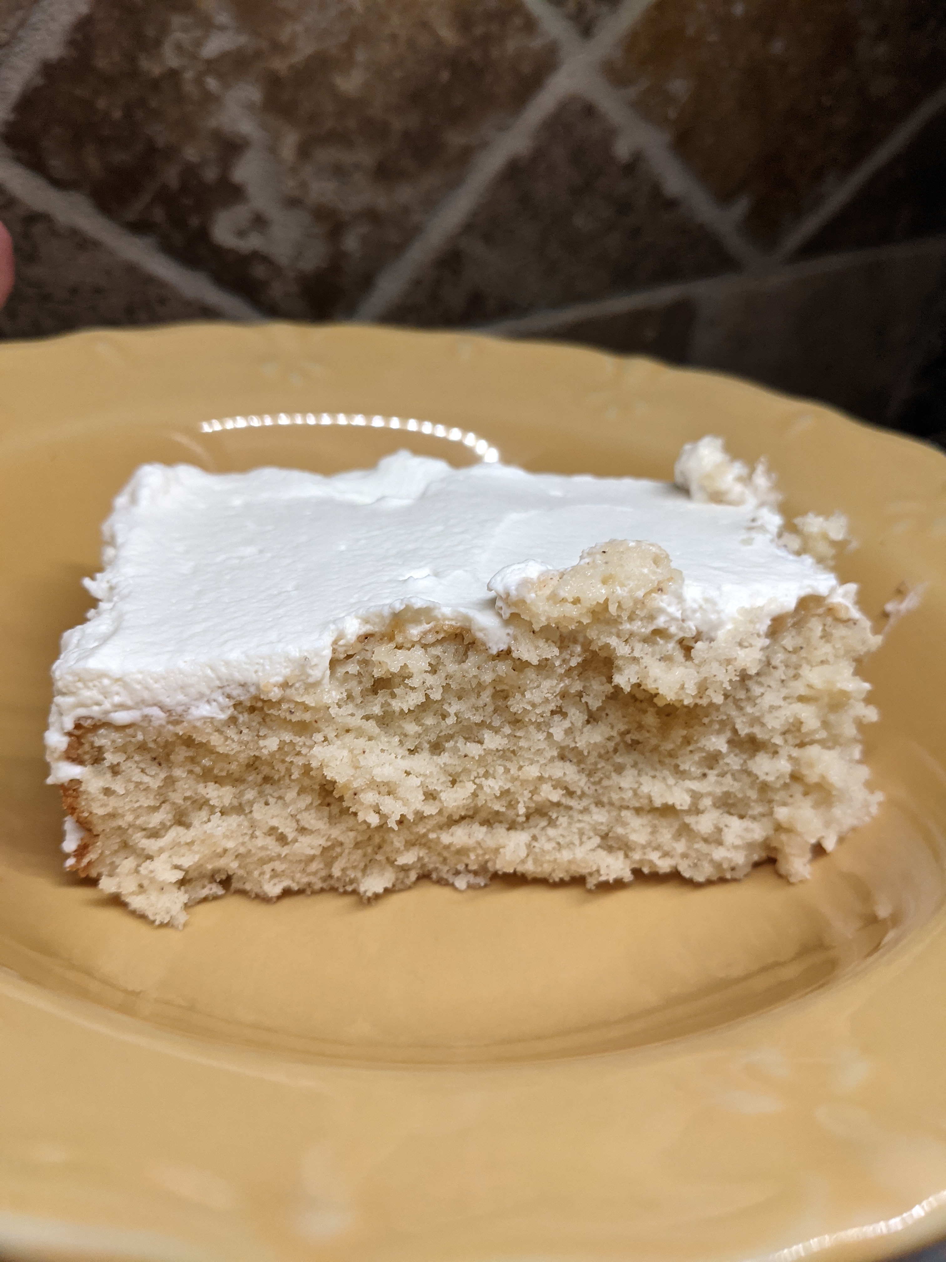 A slice of Tres Leches cake on a yellow plate.