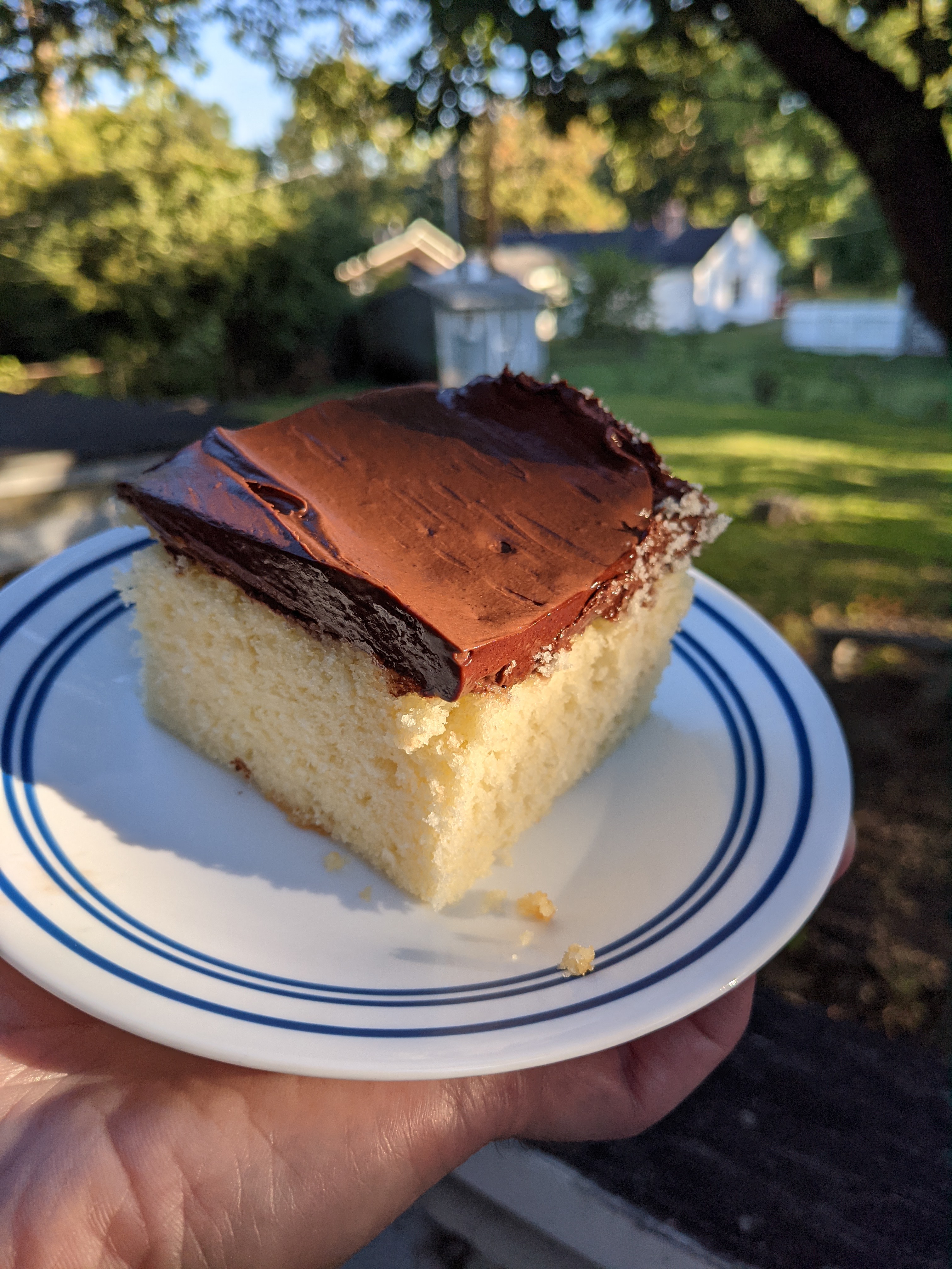 A slice of yellow sheet cake with chocolate frosting